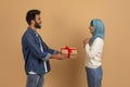 Loving arab man giving wrapped gift box to his delighted muslim girlfriend Royalty Free Stock Photo