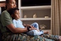 Loving Army Mother In Uniform Home On Leave Sitting On Sofa Hugging Son In Family Lounge