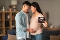 Loving asian couple hugging showing ultrasound embryo image at home Royalty Free Stock Photo