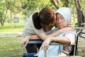 Loving asian daughter is hugging and kissing on the cheeks of her senior mother who is Alzheimer`s or is a severe depression,