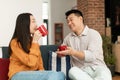Loving asian spouses drinking coffee and chatting, sitting on sofa at home, enjoying spending time together on weekend Royalty Free Stock Photo