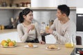 Loving asian spouses having conversation while eating at kitchen