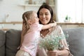 Daughter cuddle mother make pleasant surprise for her gave flowers Royalty Free Stock Photo