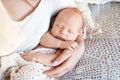 Loving baby sleeping in mother`s hands. Closeup picture. Happy mother and her slipping newborn baby in the bed