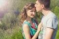 Loving beautiful couple of guys and girls in the field walking man kissing the girls forehead