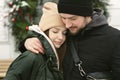 Loving beautiful couple on a winter day. A man hugging his happy woman, drinking hot tea or coffee while walking in the Royalty Free Stock Photo