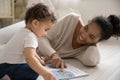 Loving biracial mom reading book with small baby toddler Royalty Free Stock Photo