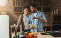 Loving black couple cooking green salad in kitchen