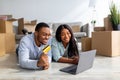 Loving black couple with laptop and credit card choosing furniture after moving to new home, free space Royalty Free Stock Photo