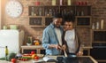 Loving black couple preparing meal together in modern kitchen