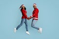 Loving black couple in Santa hats jumping up together Royalty Free Stock Photo