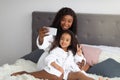 Loving black mother and cute daughter taking selfie in bath robes on bed at home. Mom and kid friendship Royalty Free Stock Photo