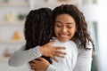 Loving black mother hugging her daughter, home interior Royalty Free Stock Photo