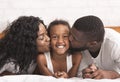 Loving black parents kissing cheeks of their happy little daughter Royalty Free Stock Photo