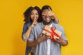 Loving black woman covering her boyfriend`s eyes and giving him gift Royalty Free Stock Photo