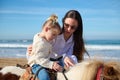 Loving caring mother teaching her daughter to ride a horse pony on the beach Royalty Free Stock Photo