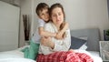 Loving and caring son comforting and hugging his mother sitting on bed. Concept of loving family, parents and kids, love and Royalty Free Stock Photo