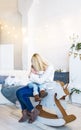 Loving caucasian mother holding her sleeping little baby daughter. Mother with sleeping baby sit on a toy wooden horse. Royalty Free Stock Photo