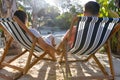 Loving caucasian young couple holding hands and relaxing on deck chairs at beach Royalty Free Stock Photo