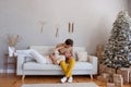 Loving, cheerful couple on a sofa near Christmas tree with gifts sits on a white sofa. Crazy lovers