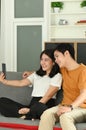 Loving cheerful happy couple taking selfie in living room.