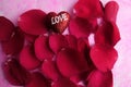 LOVING CONCEPT with red rose petals and printed word of LOVE on the red heart shape Royalty Free Stock Photo