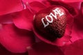 LOVING CONCEPT with red rose petals and printed word of LOVE on the red heart shape. Royalty Free Stock Photo