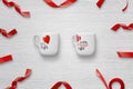 Loving couple cups with red decorations on white wooden table