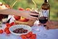 Loving couple drinking red wine from transparent glasses, wedding day, outdoor picnic with sweet candy and fruit