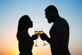 Loving couple drinking wine or champagne during sunset time, silhouette of a couple with wineglasses on sunset background, man and Royalty Free Stock Photo