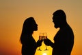 Loving couple drinking wine or champagne during sunset time, silhouette of a couple with wineglasses on sunset background, man and Royalty Free Stock Photo