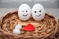 A loving couple of eggs with emoticons and a heart on a wooden basket. Royalty Free Stock Photo