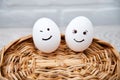 Loving couple of eggs with emoticons on a wooden basket. Royalty Free Stock Photo