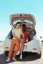 Loving couple feeling unbelievable sitting near trunk of their car Royalty Free Stock Photo