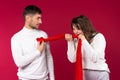 A loving couple fooling around on red background. Lovers pastime concept. Girl snatches the boy`s heart from his chest Royalty Free Stock Photo