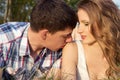 Loving couple of guys and girls lying on the grass on the meadow, man kissing a girl on the shoulder