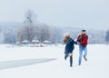 Loving couple is having fun while dancing on the meadow covered with snow during the snowfall. Royalty Free Stock Photo