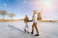 Loving couple having fun on ice in typical dutch landscape with windmill. Woman and man ice skating outdoors in sunny Royalty Free Stock Photo