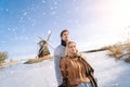 Loving couple having fun on ice in typical dutch landscape with windmill. Woman and man ice skating outdoors in sunny Royalty Free Stock Photo