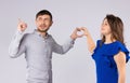 A loving couple holds a heart from hands on a white background. The man points his finger to the top