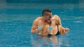 The loving couple hugs and kisses, drinking blue cocktail alcohol liquor in swimming pool at hotel outdoor. Portrait of Royalty Free Stock Photo