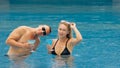 The loving couple hugs and kisses, drinking blue cocktail alcohol liquor in swimming pool at hotel outdoor. Portrait of Royalty Free Stock Photo