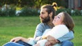 Loving couple hugs and kisses while sitting on the grass in the park. Concept. Sweet and beautiful man and woman Royalty Free Stock Photo