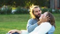 Loving couple hugs and kisses while sitting on the grass in the park. Concept. Sweet and beautiful man and woman Royalty Free Stock Photo