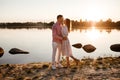 Loving couple kissing on the lake at sunset. Beautiful young couple in love walking on the shore of the lake at sunset in the rays Royalty Free Stock Photo