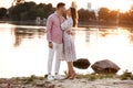 Loving couple look at each other on the lake at sunset. Beautiful young couple in love walking on the shore of the lake at sunset Royalty Free Stock Photo