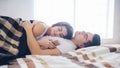 A loving couple are lying on the bed. A woman is using a smartphone