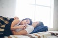 A loving couple arelying on the bed. A woman is using a smartphone