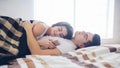 A loving couple is lying on the bed. A woman is using a smartphone