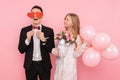 A loving couple, a man holding two paper hearts in his eyes, and a woman holding a bouquet of flowers, on a pink background Royalty Free Stock Photo